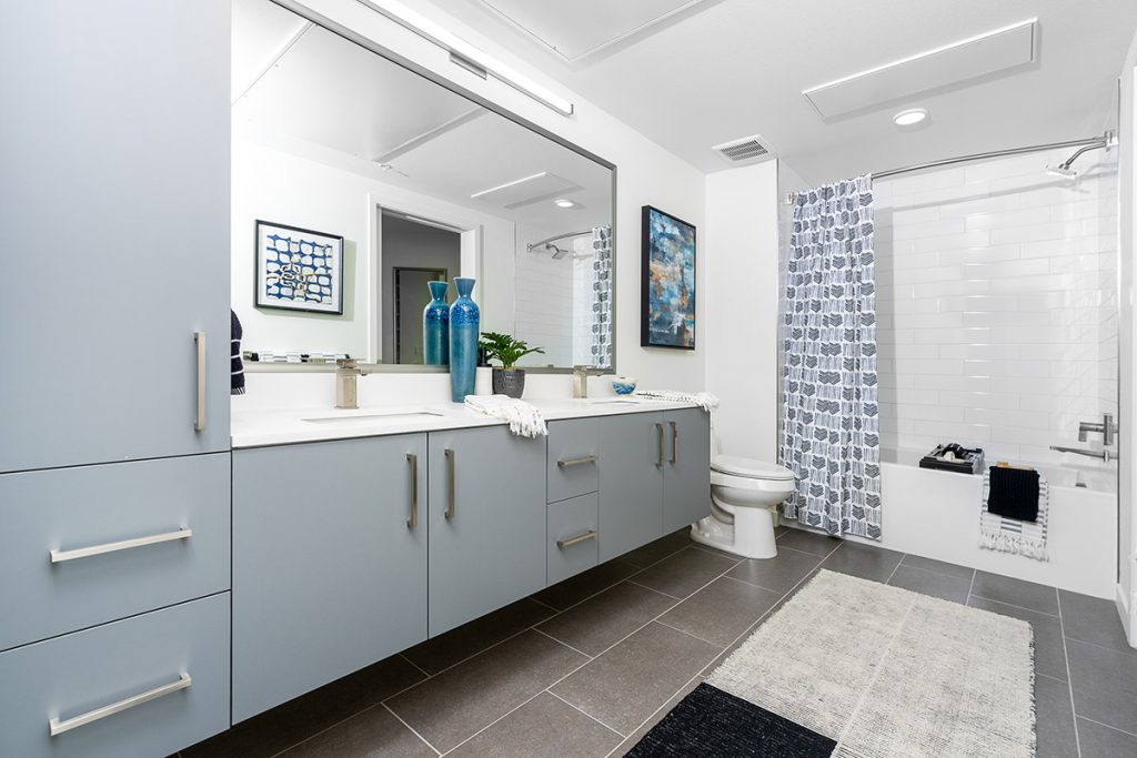 Modern bathroom with floating vanity, custom cabinetry, bathtub and designer lighting at Legacy at Livermore CA apartments.