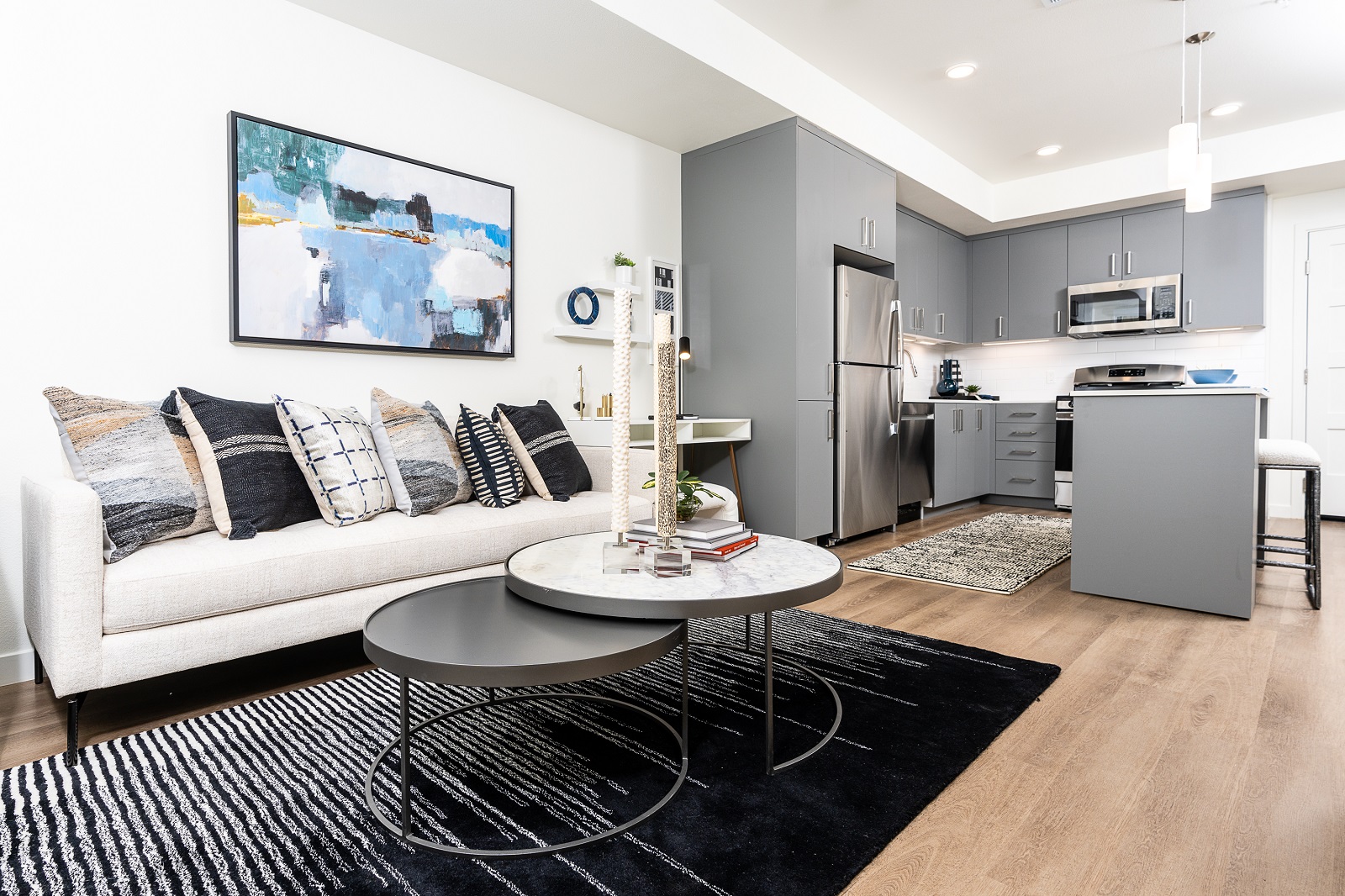 Bright living room and kitchen area in Legacy at Livermore apartments, with abstract wall art and modern kitchen appliances.