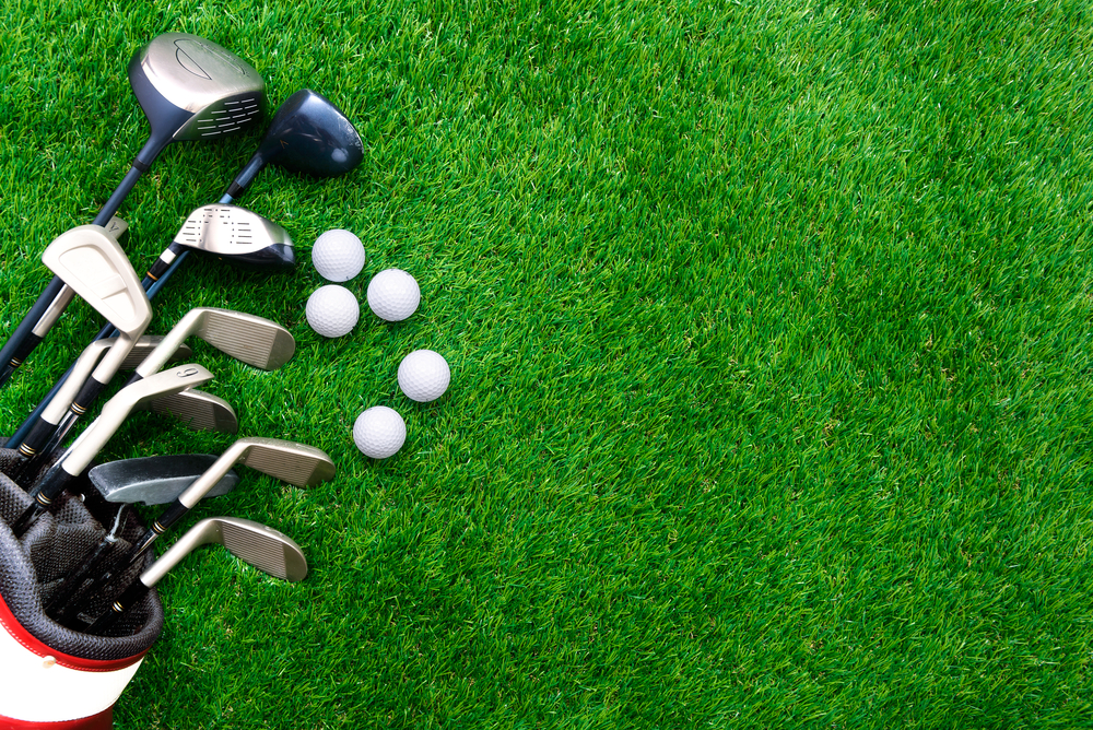Golf clubs and balls lying on green grass.